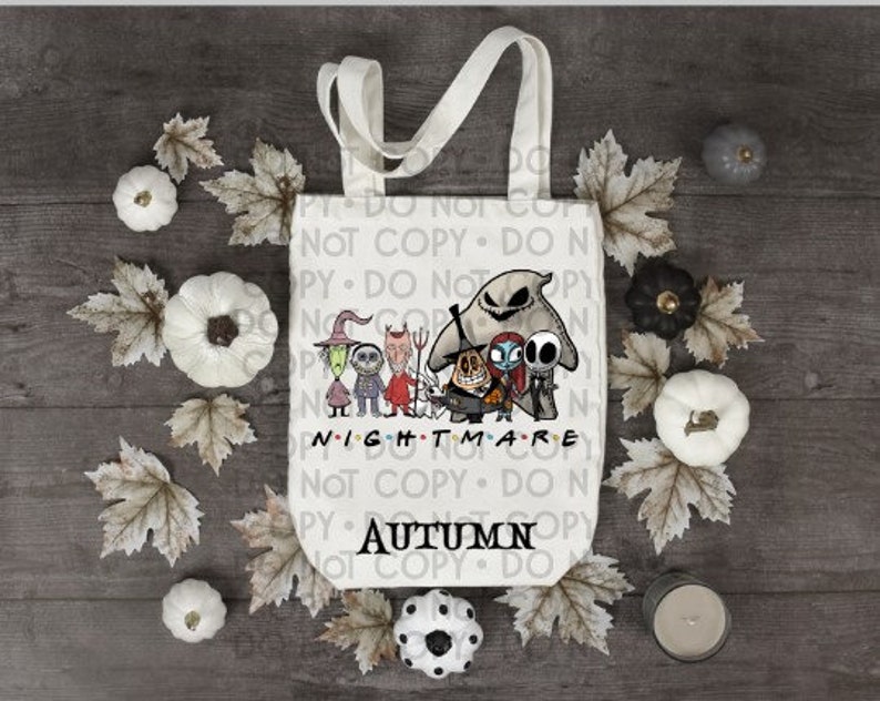 Op de afbeelding: Een witte canvas draagtas met een kleurrijke afbeelding van personages uit The Nightmare Before Christmas, waaronder Jack Skellington, Sally en Oogie Boogie. De tekst Nightmare en Autumn is in het zwart op de tas gedrukt.