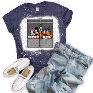 Può includere: Una maglietta blu con un designo schizzato di candeggina che presenta Topolino, Minnie Mouse, Paperino e Pluto in un ascensore grigio. I personaggi sono tutti sorridenti e guardano fuori dall'ascensore.