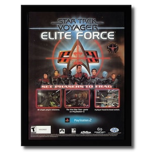 Puede incluir: Póster enmarcado de Star Trek Voyager Elite Force. El póster presenta el logotipo de Star Trek, imágenes de personajes y el texto "SET PHASERS TO FRAG". También incluye detalles del juego, como 40 misiones para un jugador y acción de 4 jugadores.