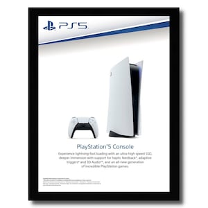 May include: A framed advertisement for the PlayStation 5 console. The image features the console, a white and black controller, and the PlayStation logo. Text on the ad highlights features like lightning-fast loading and haptic feedback.
