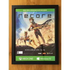 Könnte beinhalten: Ein gerahmtes Poster für das Videospiel "ReCore" mit einer weiblichen Figur, die eine Waffe hält und vor einer futuristischen Landschaft steht. Das Poster ist schwarz mit weißem Text und Logos für Xbox One und Windows 10. Der Text "AVAILABLE 09.13.16" befindet sich am unteren Rand des Posters.