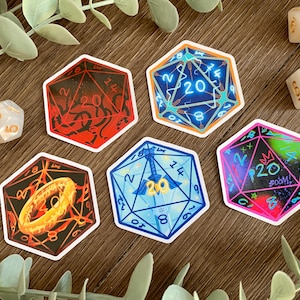 May include: Five hexagonal stickers featuring various twenty-sided die designs with unique illustrations including a golden ring, a sword, and neon patterns, accompanied by three small white polyhedral dice with gold numbers on a wooden surface.