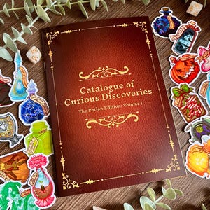 May include: A brown book titled "Catalogue of Curious Discoveries, The Potion Edition: Volume 1" with gold lettering and decorative borders. Colorful potion stickers and dice surround the book, creating a fantasy theme.