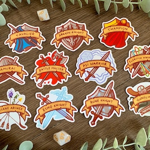 May include: Twelve colorful stickers featuring different fantasy character classes, each with a unique weapon and shield design. The stickers include "Cavalier", "Dragon Knight", "Champion", "Samurai", "Arcane Archer", "Battle Master", "Psi Warrior", "Eldritch Knight", "Echo Knight", "Rune Knight", and "Gunslinger".