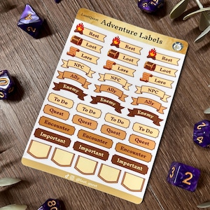 Può includere: Un foglio di adesivi con "Adventure Labels" per giochi di ruolo da tavolo. Le etichette includono "Rest", "Loot", "NPC", "Enemy" e "Quest". Il foglio è circondato da dadi viola e vegetazione. Misure in cm.