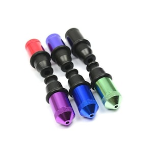 May include: Four metal smoking pipes with black rubber tips. The pipes are red, blue, purple, and green.