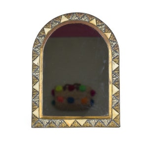 Op de afbeelding: Een gouden en witte boogspiegel met een decoratief geometrisch patroon rond de lijst.