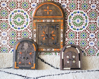 May include: Three ornate, arched, decorative mirrors with intricate metalwork and colorful accents. The mirrors are set against a background of white, green, blue, and brown patterned tiles.
