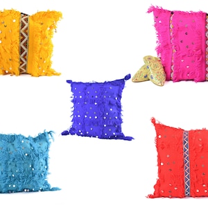 Puede incluir: Cinco cojines decorativos con flecos y adornos de espejo. Los cojines son de varios colores, incluyendo amarillo, rosa, azul, turquesa y rojo.