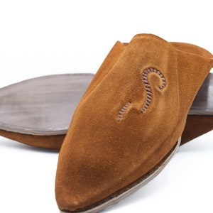 Peut inclure: Une paire de pantoufles en daim marron avec une pointe pointue et un motif brod&eacute; d&eacute;coratif. Les pantoufles sont faites d'un mat&eacute;riau doux et confortable et ont un design simple et &eacute;l&eacute;gant.
