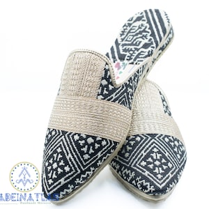 May include: A pair of black and white patterned slippers with a gold trim. The slippers are made of fabric and have a pointed toe.