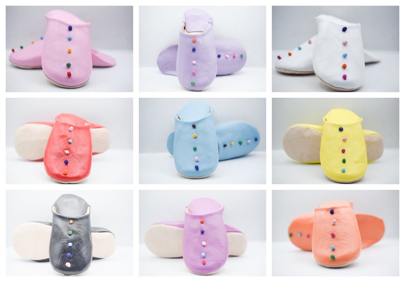 Op de afbeelding: Een verzameling kleurrijke leren slippers in verschillende tinten, waaronder roze, paars, wit, rood, blauw, geel, grijs en oranje. Elke slipper heeft een rij kleine, veelkleurige decoratieve kralen in het midden.