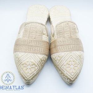 May include: A pair of gold embroidered slippers with pointed toes. The slippers have a geometric pattern and a gold band across the top.