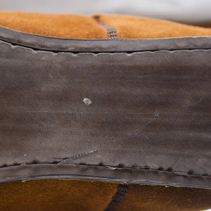 Peut inclure: Gros plan sur la semelle en daim marron d'une chaussure. La semelle est cousue avec un fil marron et a une surface textur&eacute;e.