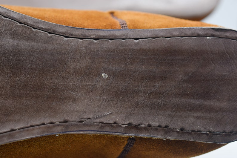 Peut inclure: Gros plan sur la semelle en daim marron d'une chaussure. La semelle est cousue avec un fil marron et a une surface textur&eacute;e.