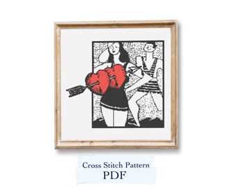 May include: Black and white cross stitch pattern of a couple holding a heart with an arrow through it. The pattern is framed in a wooden frame. The text "Cross Stitch Pattern PDF" is on a white label.