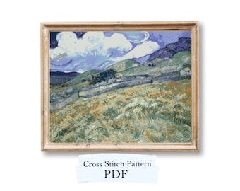 May include: A cross stitch pattern PDF of a landscape painting featuring a blue sky, white clouds, and green hills. The painting is framed in a light wood frame.