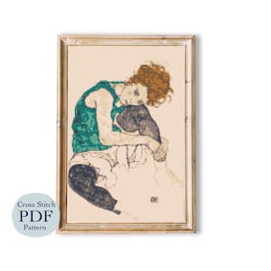 May include: Cross stitch pattern of a woman sitting with her arms around her legs, wearing a green tank top and black pants. The woman has red hair and is looking down. The background is a light beige color.