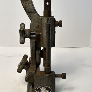 Könnte beinhalten: Ein vintage Werkzeug aus grauem Metall von Albertson & Co. Inc. Sioux mit einem vertikalen Hebel, zwei Einstellknöpfen und einer Bodenplatte. Das ovale Metallschild trägt die Aufschrift Albertson & Co. Inc. Sioux Cat. No. 7136 Made in U.S.A. Gebrauchsspuren.