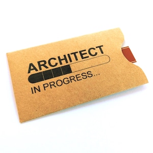 May include: A brown card with the words "ARCHITECT" above a progress bar graphic and the words "IN PROGRESS..." printed in black. The card has a small red tab on the right side.