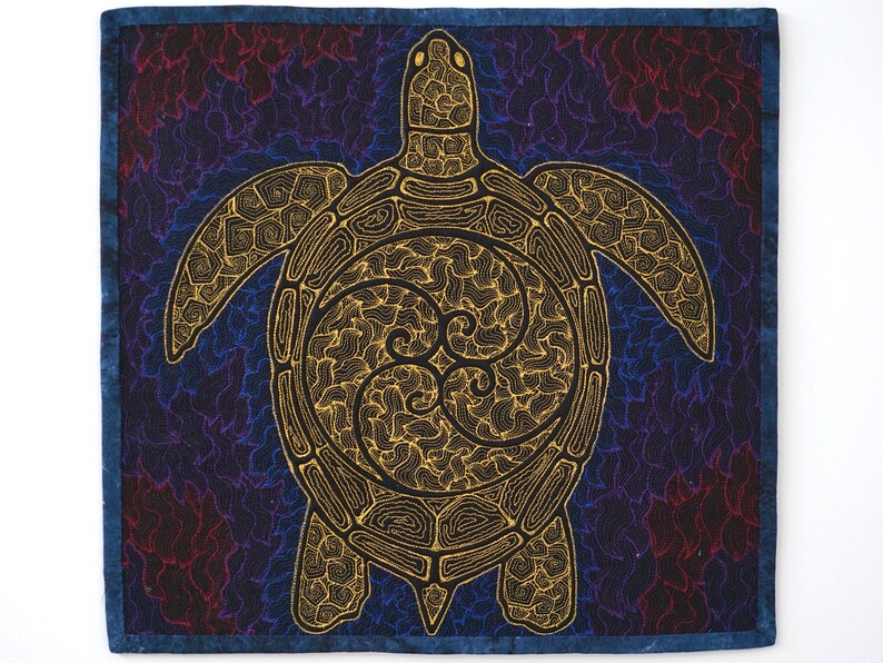 Może przedstawiać: Złota ż&oacute;łw z misternymi wzorami linii jest wyszyty na ciemnoniebieskim materiale z wirującym wzorem. Ż&oacute;łw jest wyśrodkowany na materiale i ma szczeg&oacute;łowy pancerz z wzorem tr&oacute;j-spiralnym.