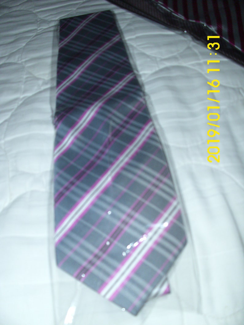 May include: A gray and pink plaid tie with a white background. The tie is folded and placed on a white surface.