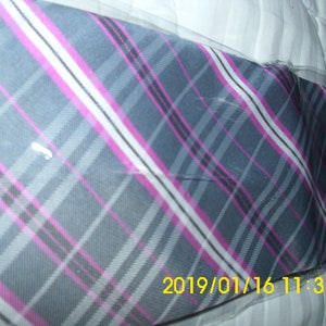 May include: A gray, pink, and white plaid tie with a diagonal pattern. The tie is wrapped in clear plastic.