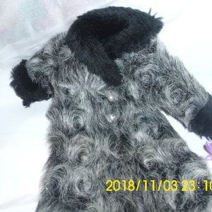 May include: A gray and black faux fur coat with a black collar. The coat has a swirl pattern and is made of soft, fluffy material.