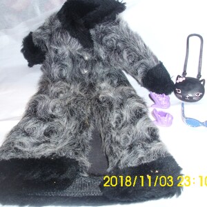 May include: A long, gray and black faux fur coat with a black cat purse, purple shoes, and blue sunglasses. The coat has a swirl pattern and a black trim.