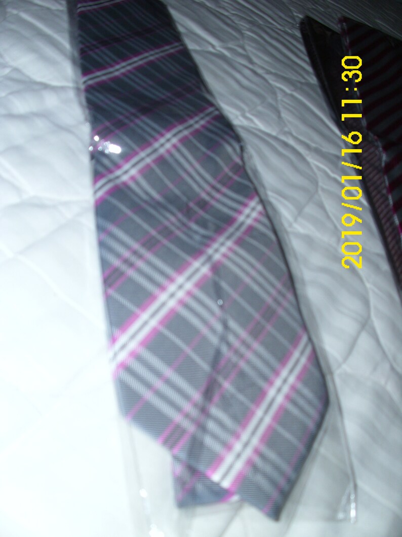 May include: A gray and pink plaid tie with a white background. The tie is packaged in plastic.