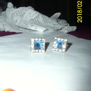 May include: A pair of silver earrings with square blue gemstones.