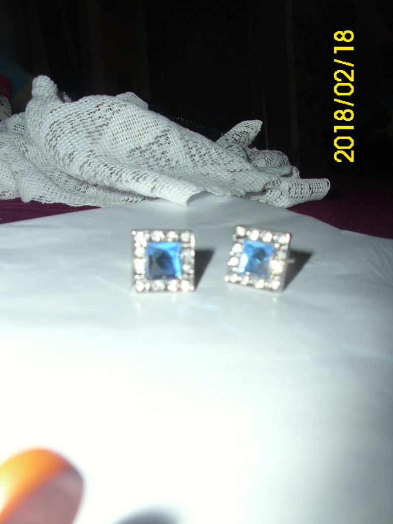 May include: A pair of silver earrings with square blue gemstones.