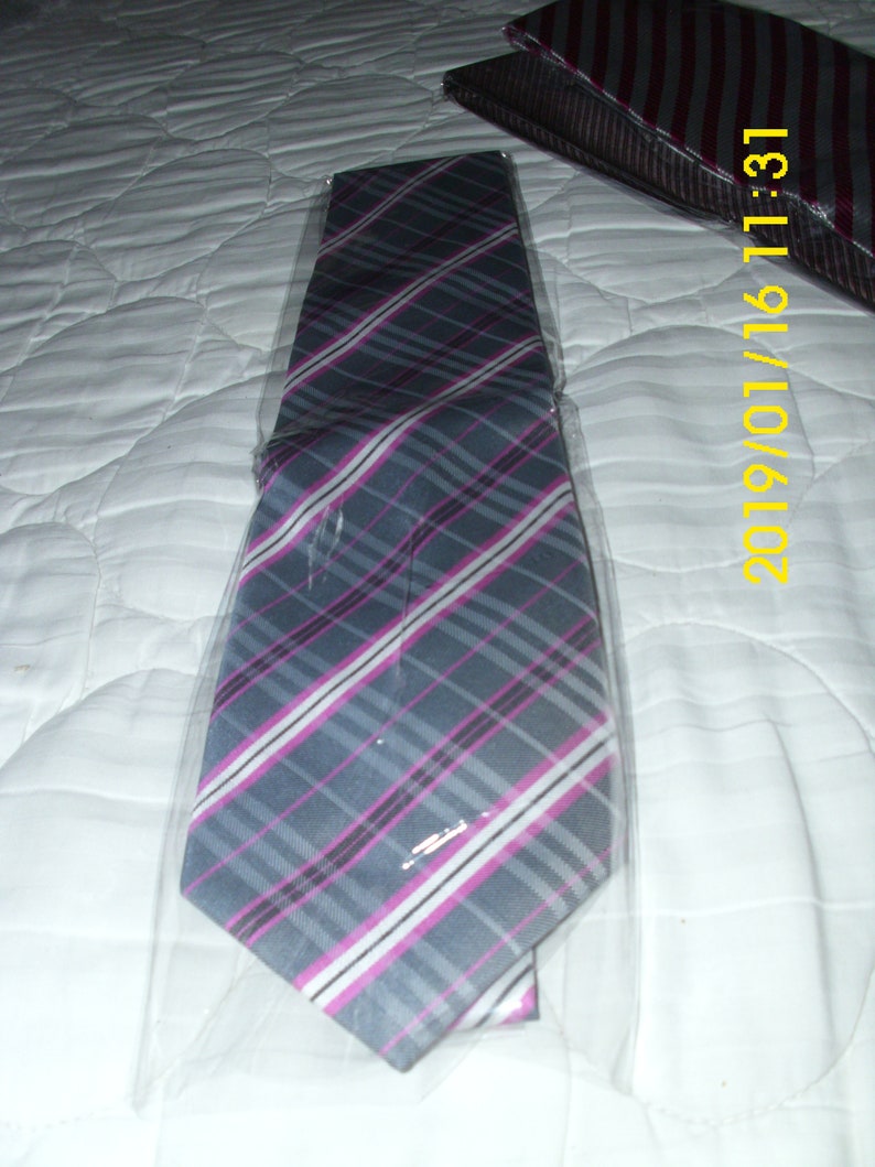 May include: A gray and pink striped tie with white stripes. The tie is packaged in a clear plastic bag.