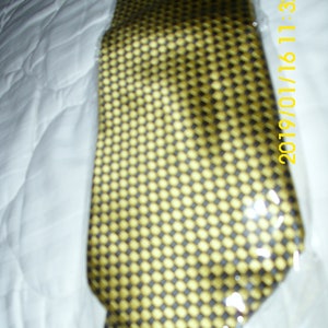 May include: A gold and black patterned tie. The tie has a geometric pattern of small squares.