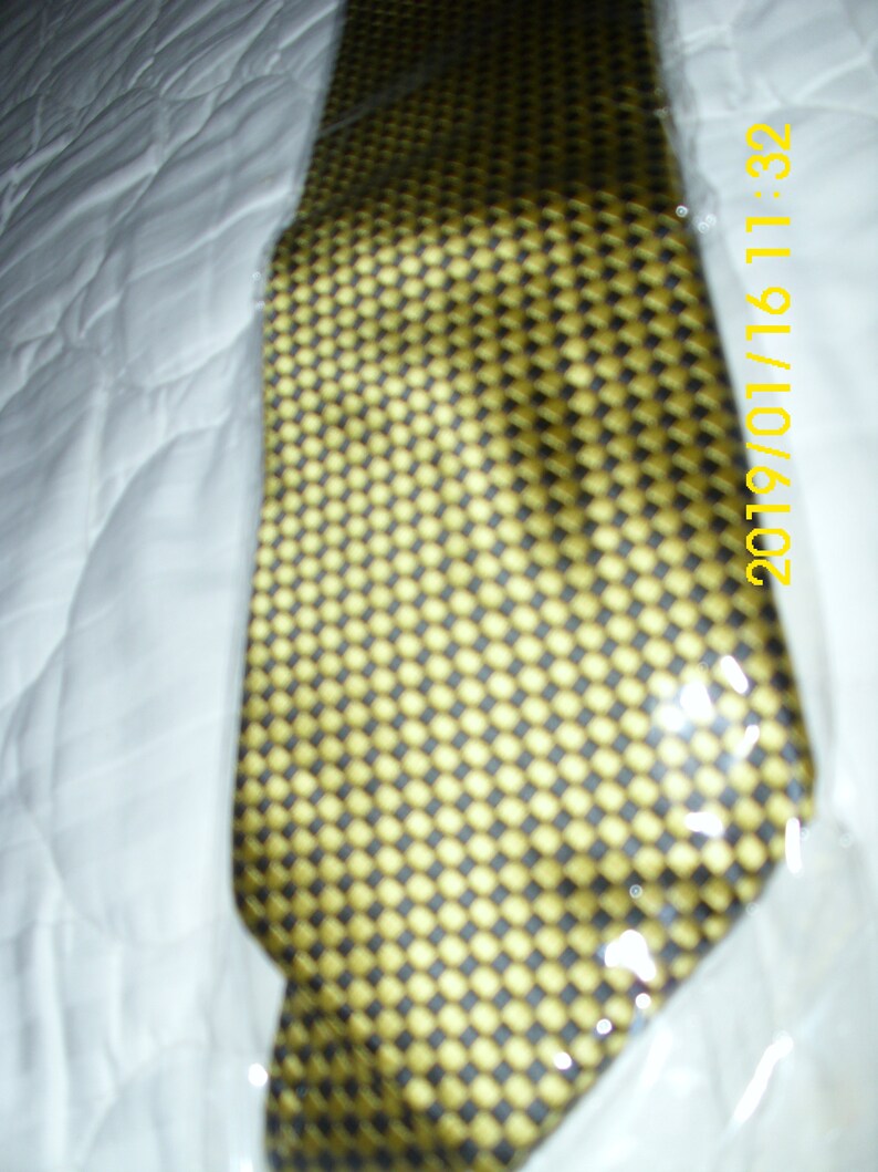 May include: A gold and black patterned tie. The tie has a geometric pattern of small squares.