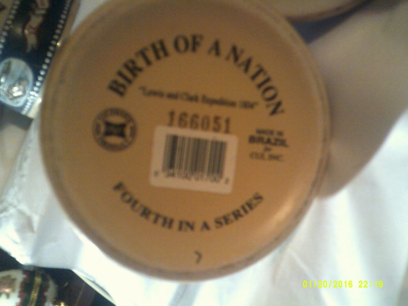 May include: A beige ceramic mug with the text "Birth of a Nation" and "Fourth in a Series" printed on the bottom. The mug also has a barcode and the text "Made in Brazil" printed on the bottom.