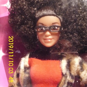 Muñeca Keniana con gran peinado afro, traje rojo y negro, abrigo con estampado animal y cartera a juego NRFB