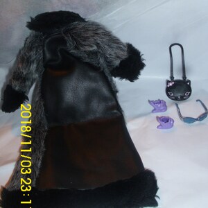 May include: A black faux fur coat with a black leather bodice and a black fur trim. The coat is laying on a white surface with a black cat purse, purple gloves, and sunglasses.