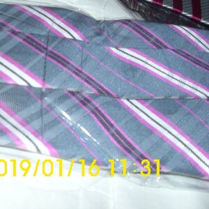 May include: A gray and white striped tie with pink stripes. The tie is wrapped in plastic and has the date 01/16/2019 and the time 11:31.