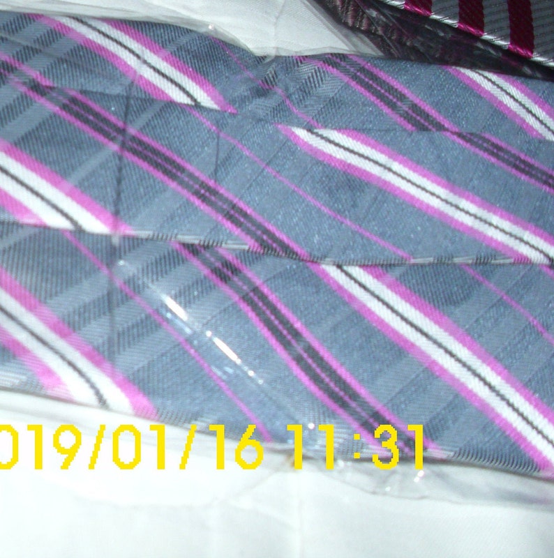 May include: A gray and white striped tie with pink stripes. The tie is wrapped in plastic and has the date 01/16/2019 and the time 11:31.
