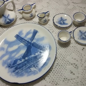 May include: A blue and white porcelain tea set with a windmill design. The set includes a teapot, creamer, sugar bowl, four teacups, and four saucers.