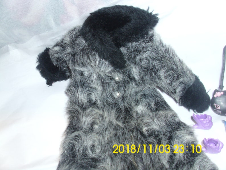 May include: A gray and black faux fur coat with a black collar. The coat has a swirl pattern and is made of soft, fluffy material.