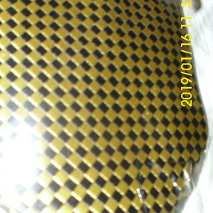 May include: A close-up of a gold and black checkered pattern. The pattern is made up of small squares. The image is slightly blurry.
