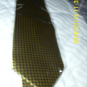May include: A gold and black patterned tie. The tie is made of a smooth, silky fabric.