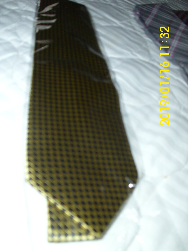 May include: A gold and black patterned tie. The tie is made of a smooth, silky fabric.