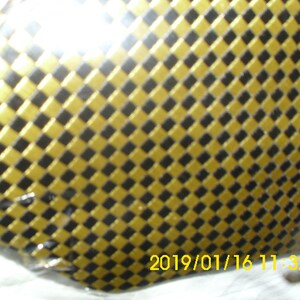 May include: A close-up of a black and gold checkered pattern. The pattern is made up of small squares, with the gold squares being slightly raised.