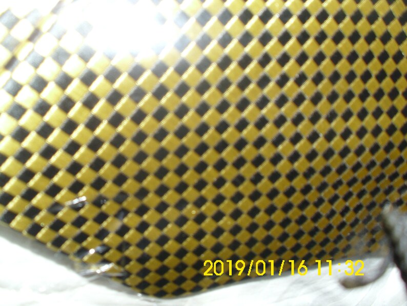 May include: A close-up of a black and gold checkered pattern. The pattern is made up of small squares, with the gold squares being slightly raised.