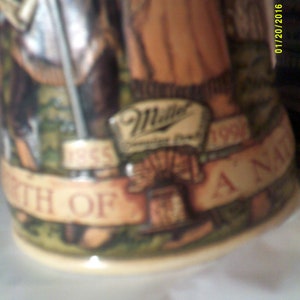 May include: A brown and white ceramic stein with a green, brown, and white design. The stein features a banner with the text "1965" and "1995" and the words "Birth of A Nation". The stein also features a logo for Miller Brewing Company.