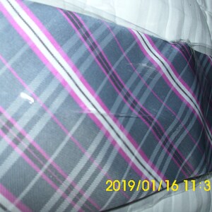 May include: A gray, pink, and white plaid tie with a diagonal pattern. The tie is wrapped in clear plastic.