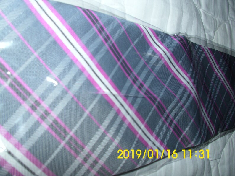 May include: A gray, pink, and white plaid tie with a diagonal pattern. The tie is wrapped in clear plastic.
